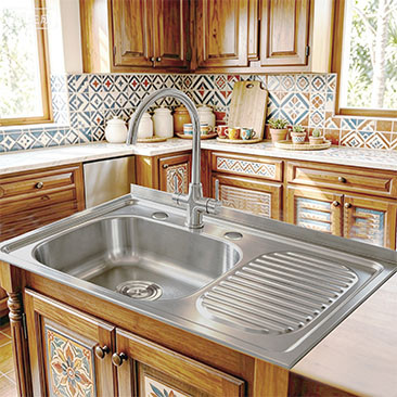 Single bowl drop-in stainless steel sink with drainboard installed in a tiled kitchen island countertop