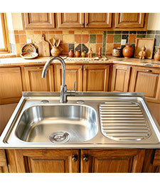 Stainless steel drainboard sink on a stone countertop in an earthy style kitchen with handmade ceramics