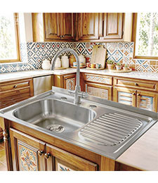Single bowl sink with drainboard fitted into a patterned tile kitchen with wooden cabinetry
