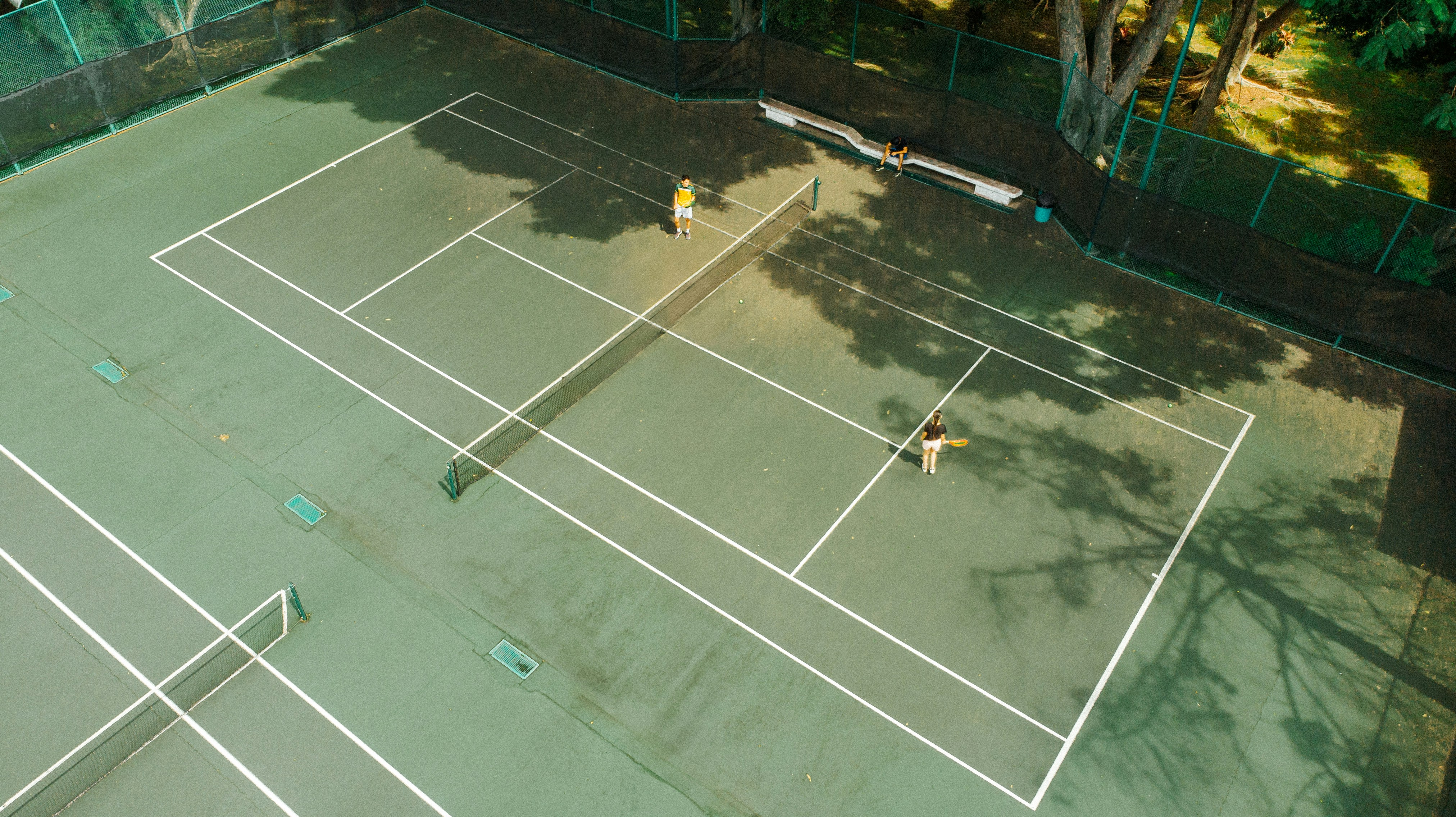 Cleaning tennis court for pickleball conversion Person pressure washing a tennis court surface