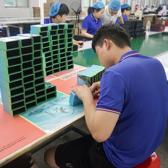 Finished custom rigid gift boxes being visually compared for color consistency during packaging quality inspection