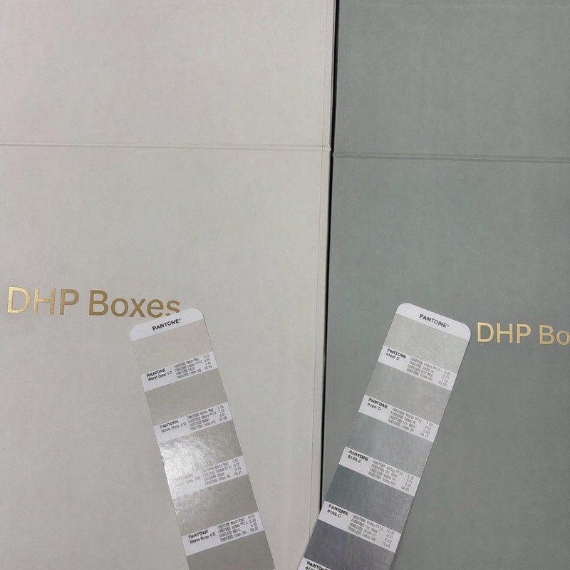 Pantone color reference cards placed against two custom magnetic gift box pre-production samples for color comparison