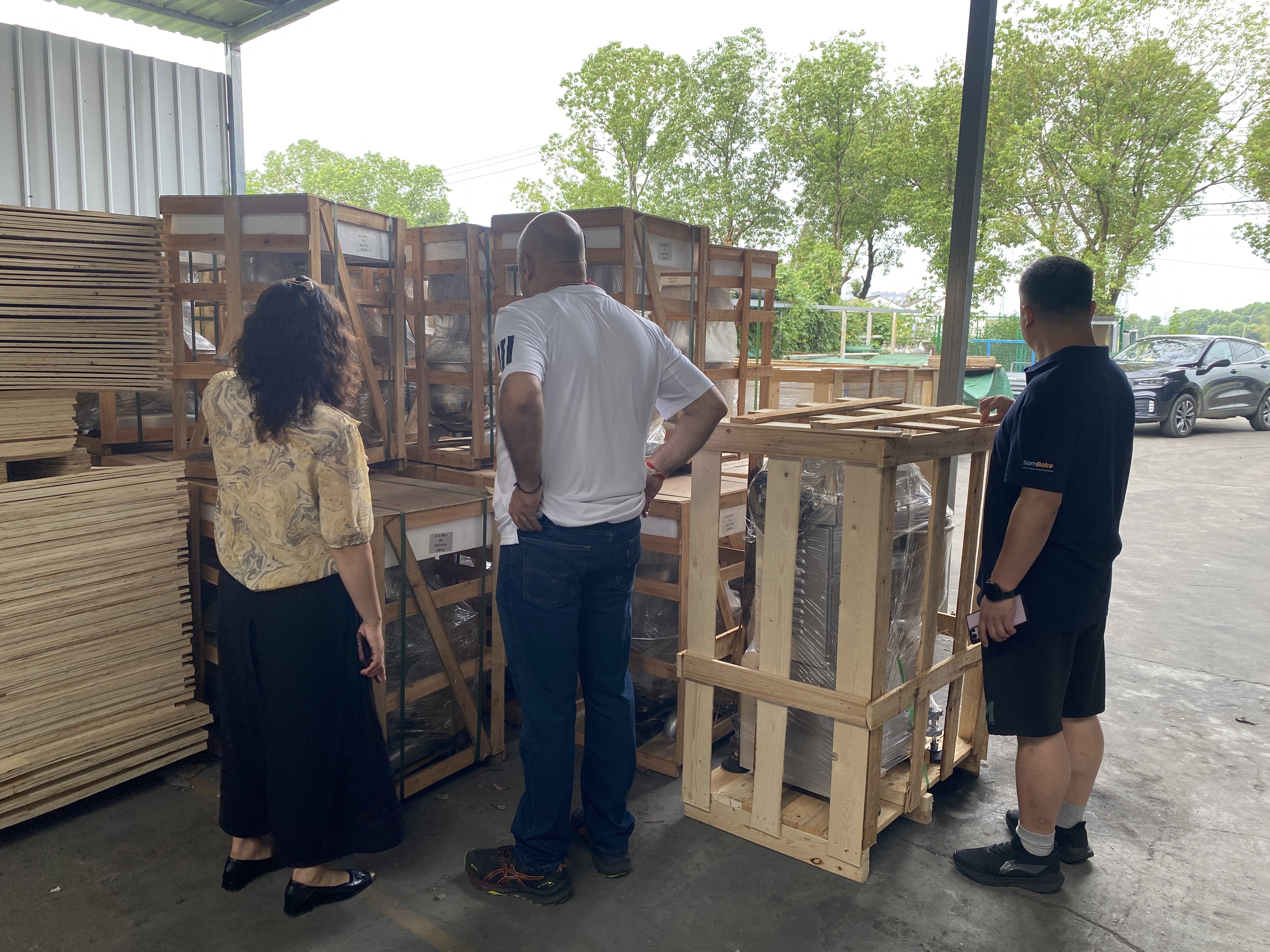 عملاء نيباليون في مصنع سامبيك يختبرون معدات المخابز مثل مضارب البيض، مع ظهور أفران سطحية تجارية في الخلفية.