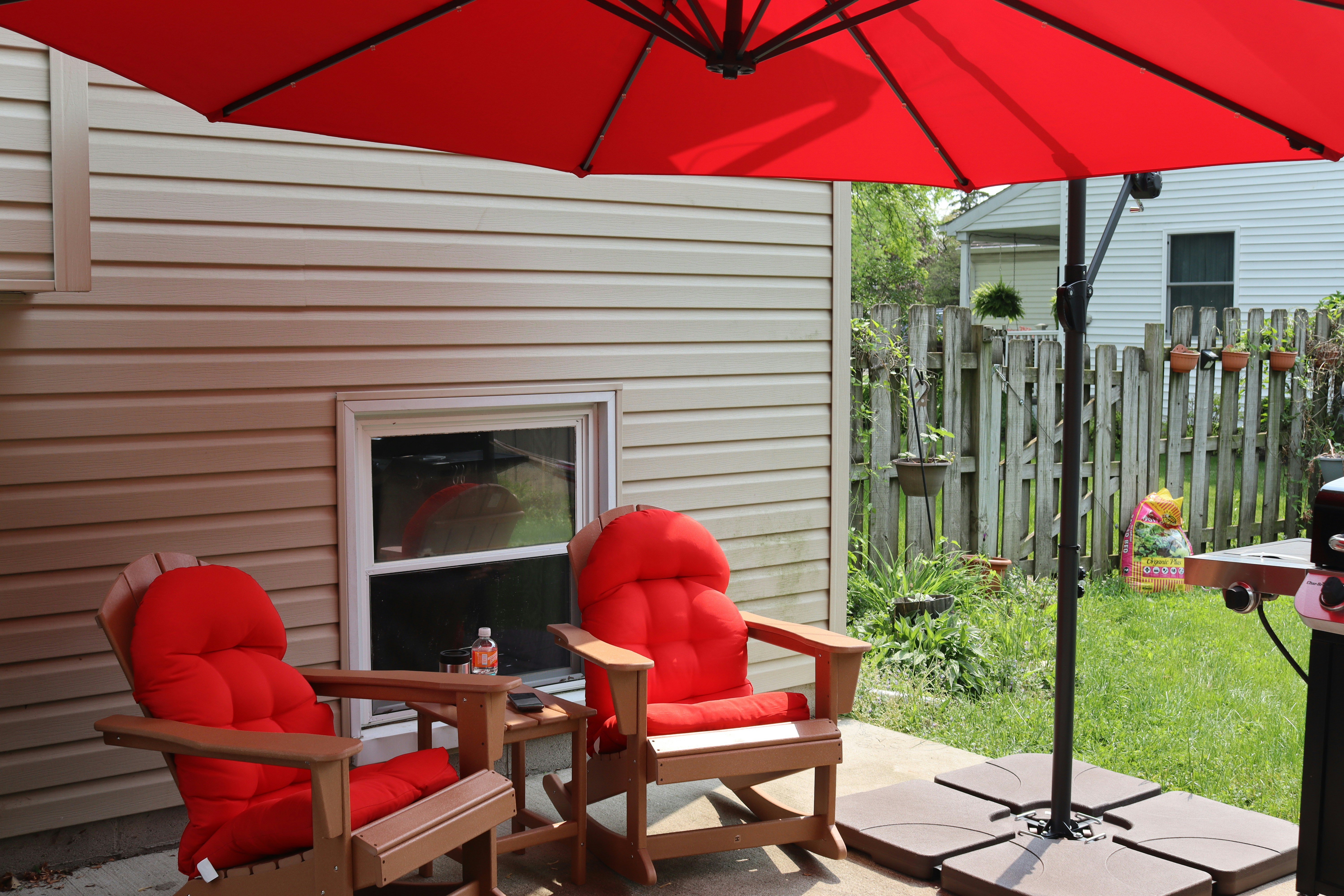 A classic market umbrella with a central pole standing in a weighted base on a sunny patio.