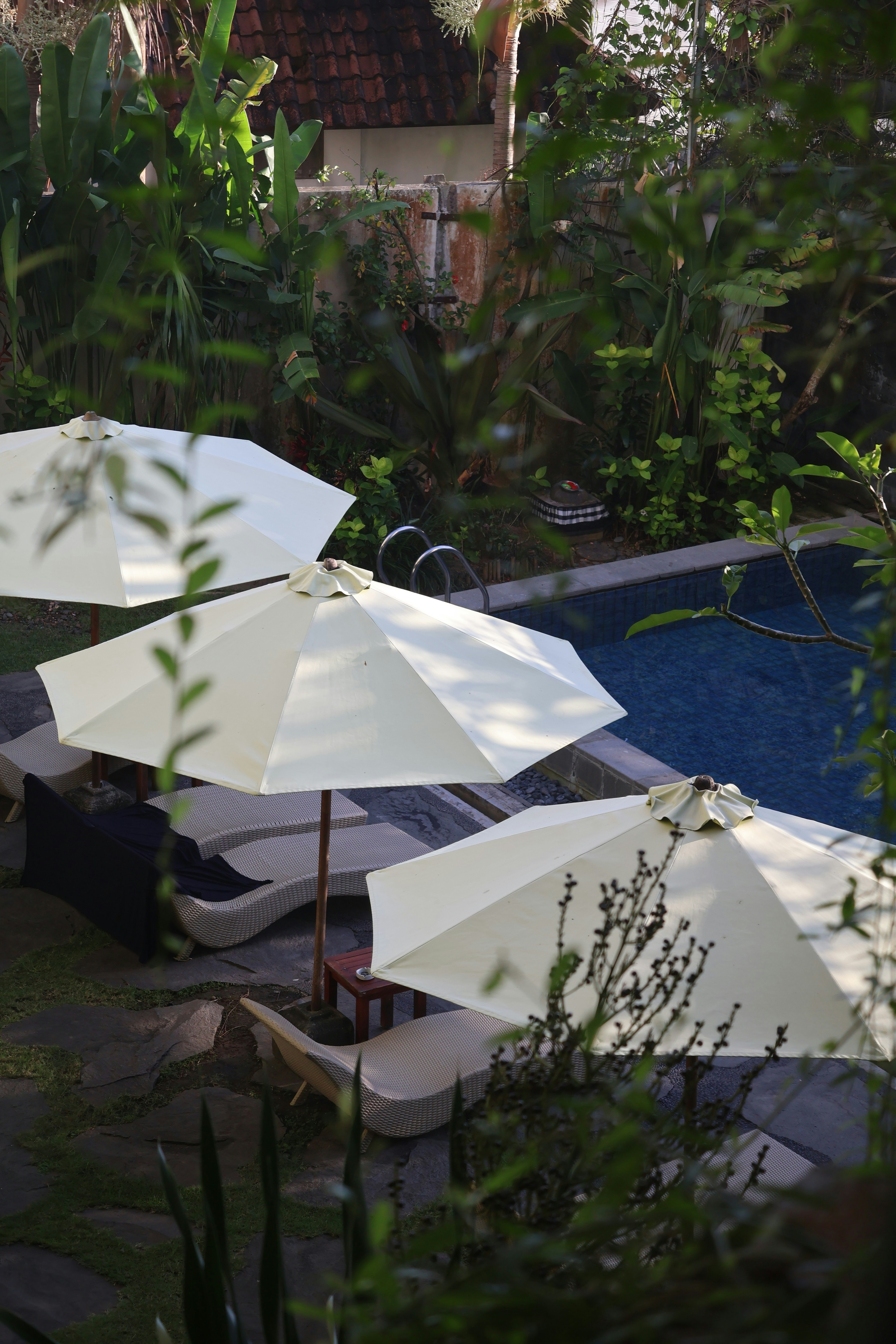 A cantilever umbrella strategically placed to shade a poolside lounge area, tracking the afternoon sun.