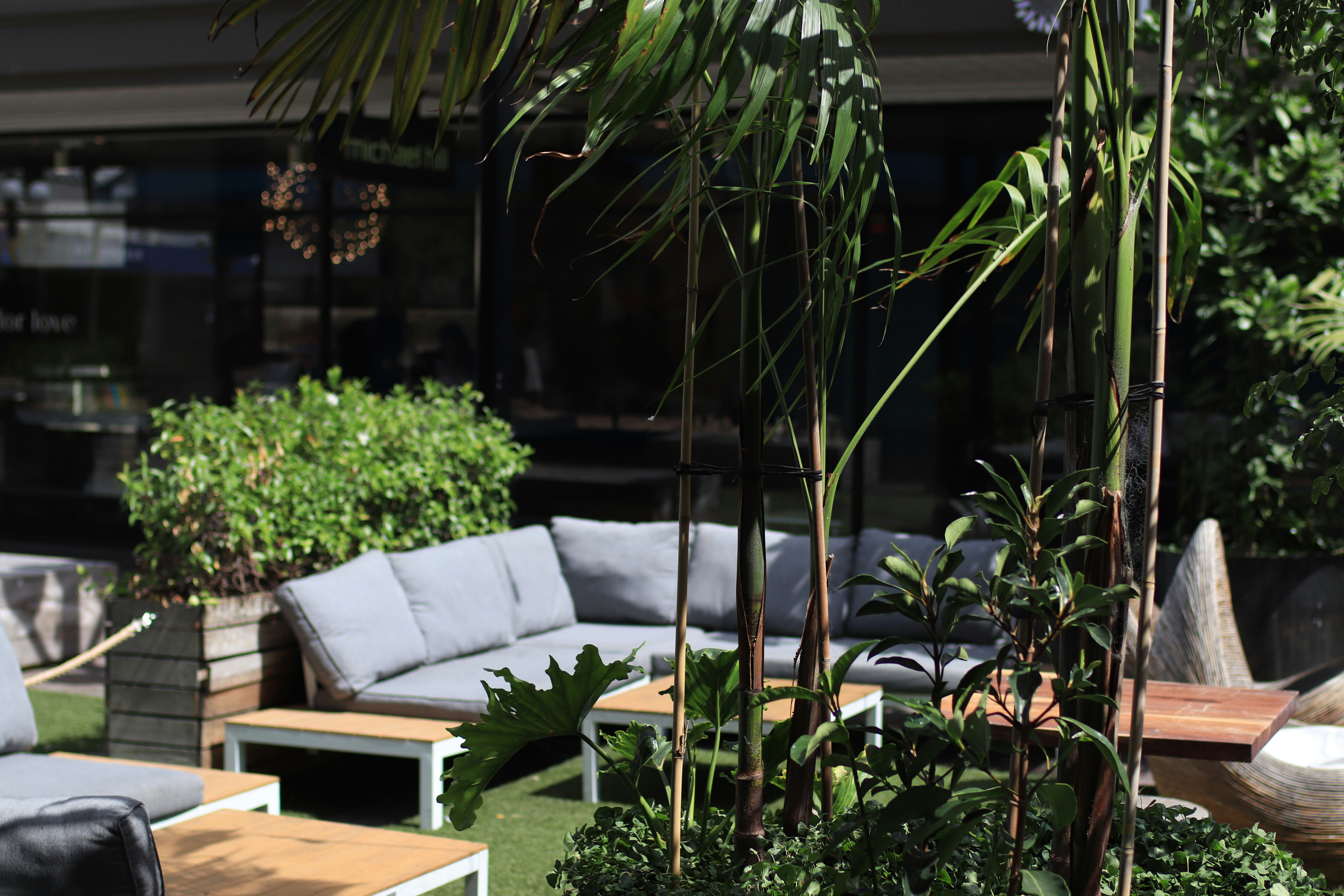 A large square cantilever umbrella with a side post, providing unobstructed shade over a comfortable outdoor lounge seating area.