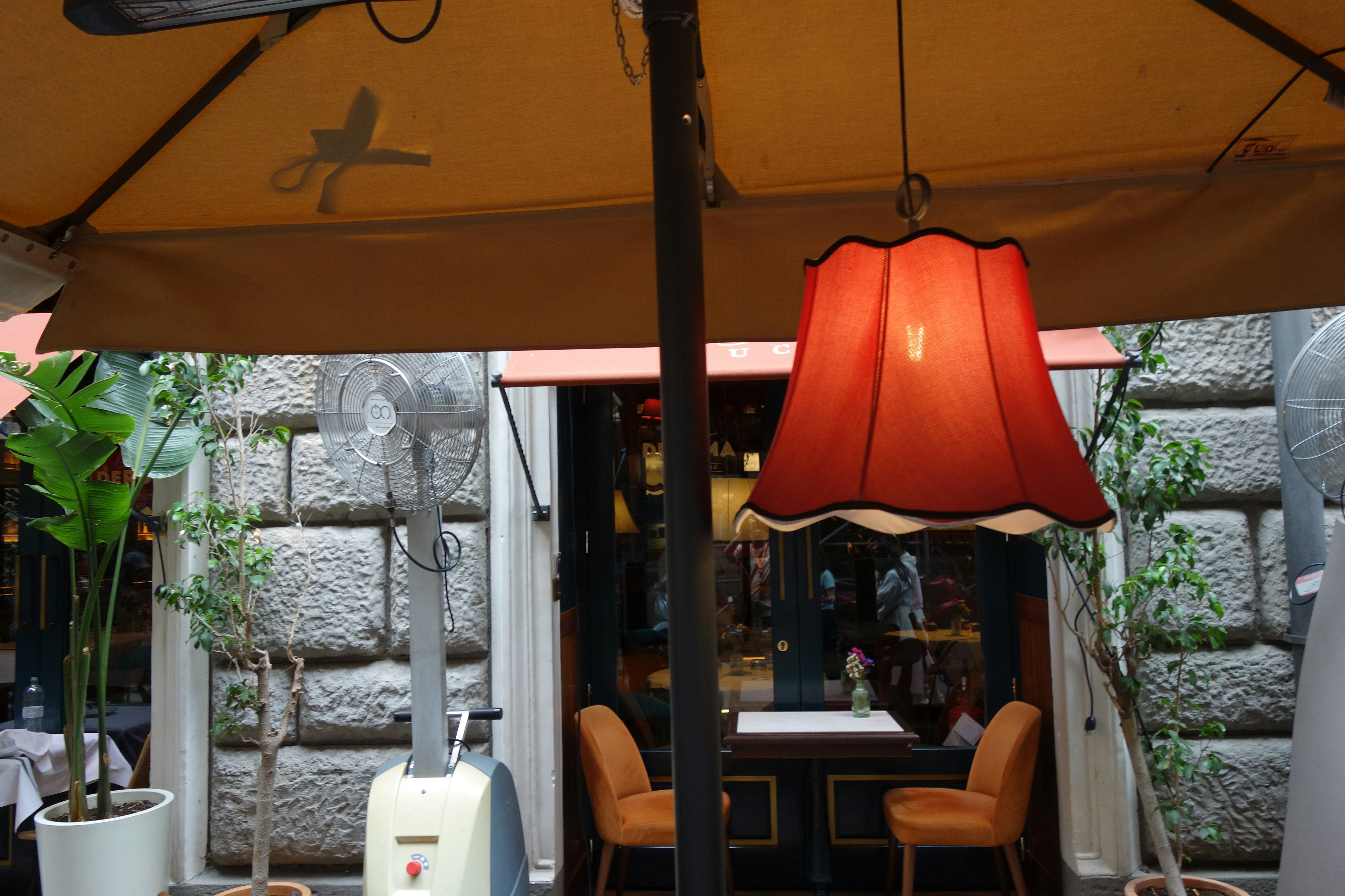 alt='Classic market umbrella with center pole through a dining table' A classic market umbrella placed in the center of an outdoor dining table