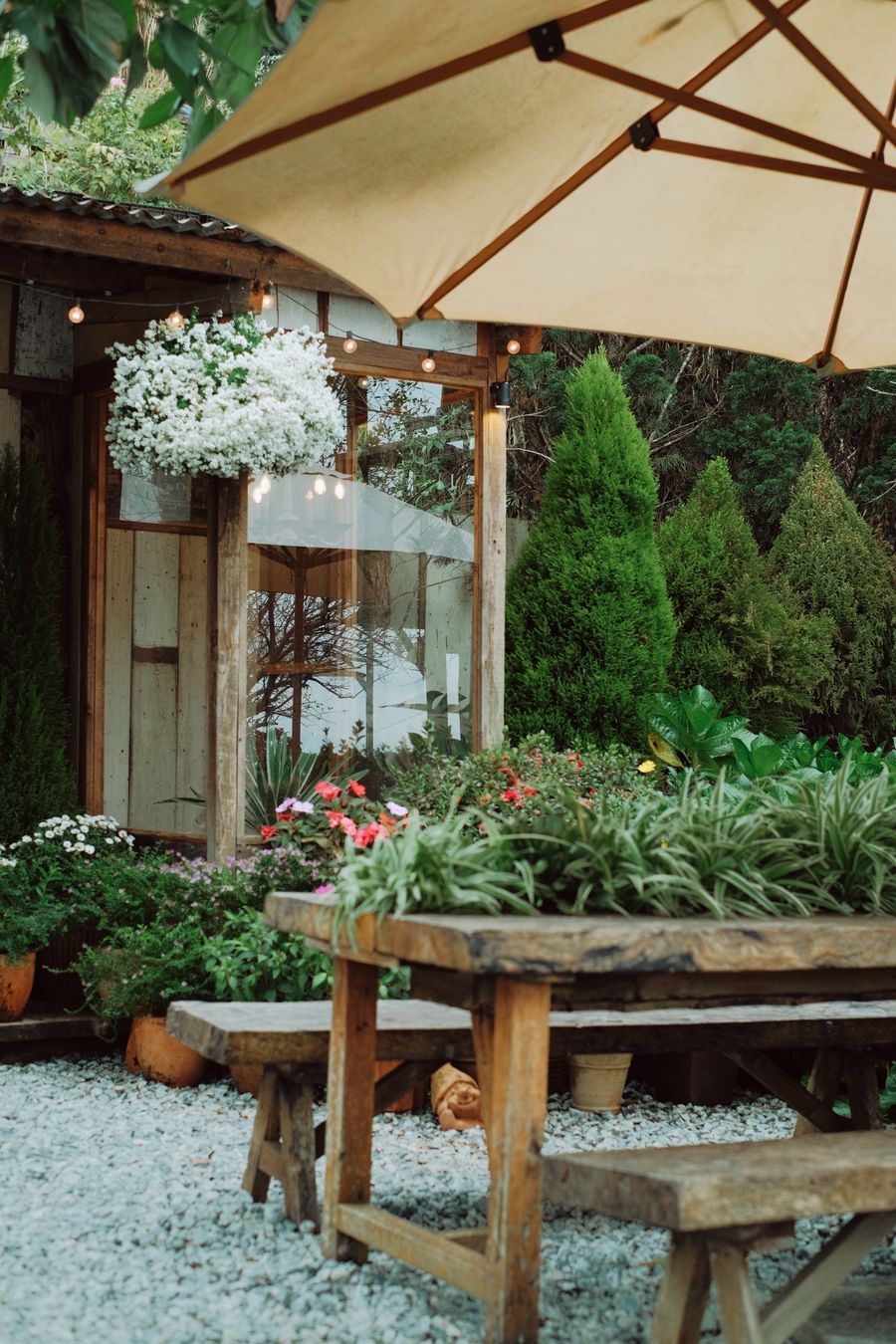 Rustic garden patio with wooden furniture, flowers and a large patio umbrella