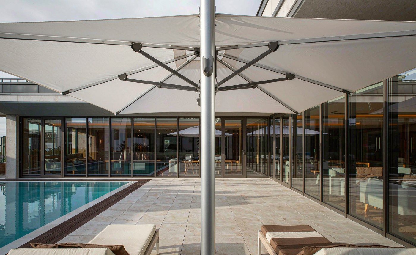 A large architectural shade umbrella on a luxury hotel terrace