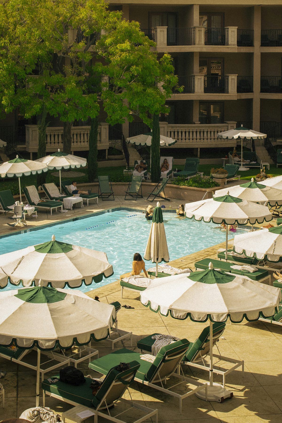 White umbrellas shading a pool surrounded by green trees