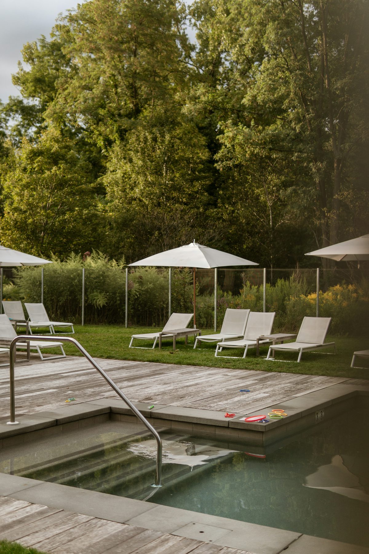 Resort pool deck with sun loungers and umbrellas on a timber deck
