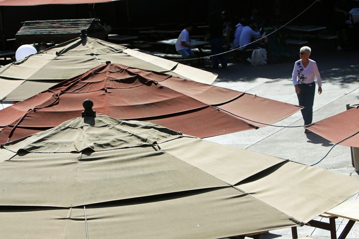 Outdoor cafe tables shaded by umbrellas on a paved terrace
