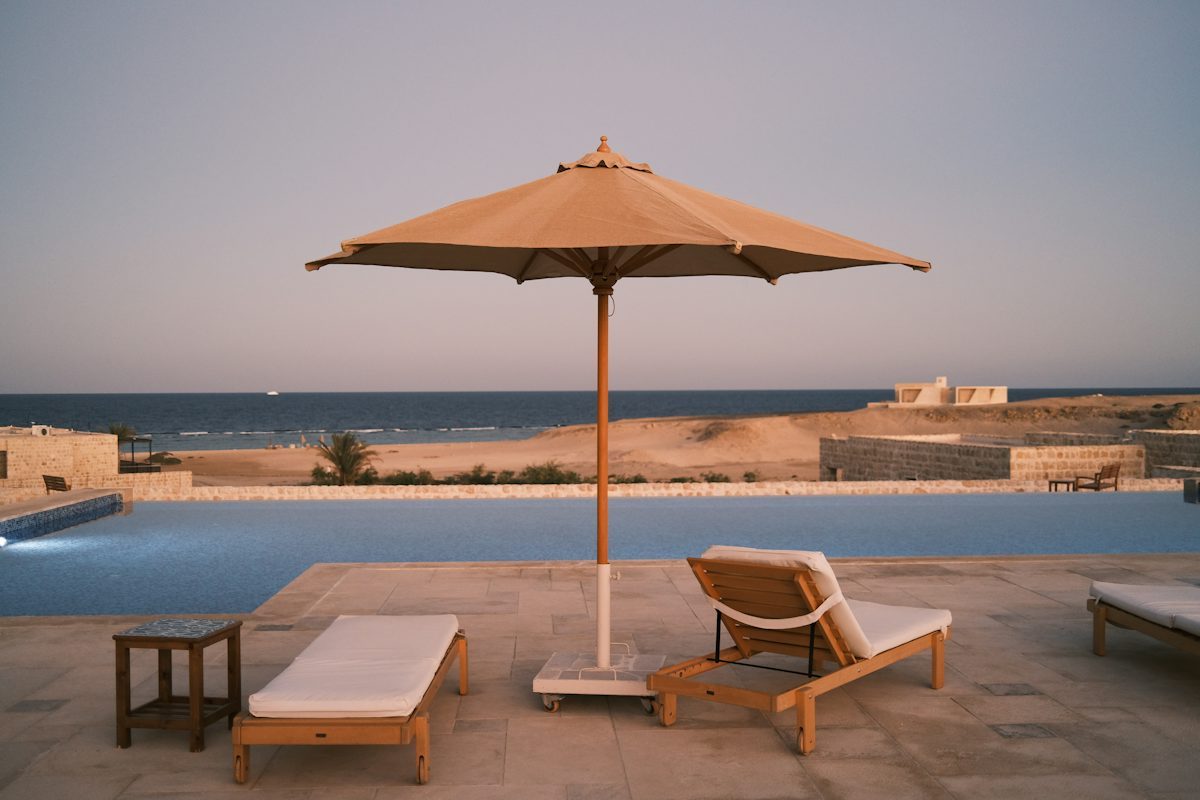 Two sun loungers and an umbrella on an exposed pool deck overlooking the sea