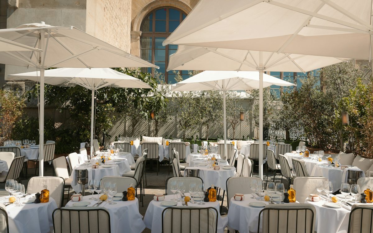 Restaurant terrace with white set tables shaded by umbrellas