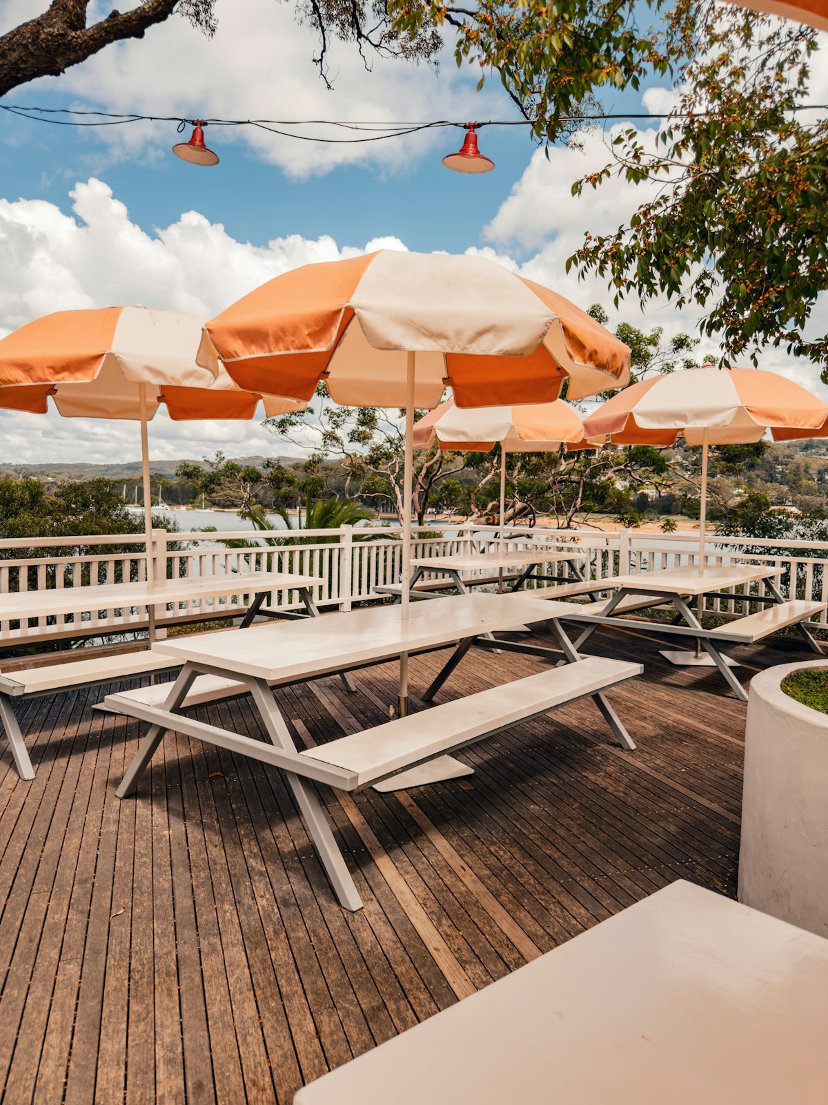 Wooden deck with picnic tables under orange umbrellas