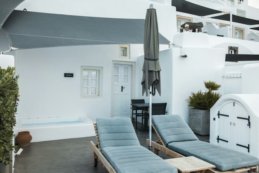 White terrace with a parasol on a freestanding base beside loungers