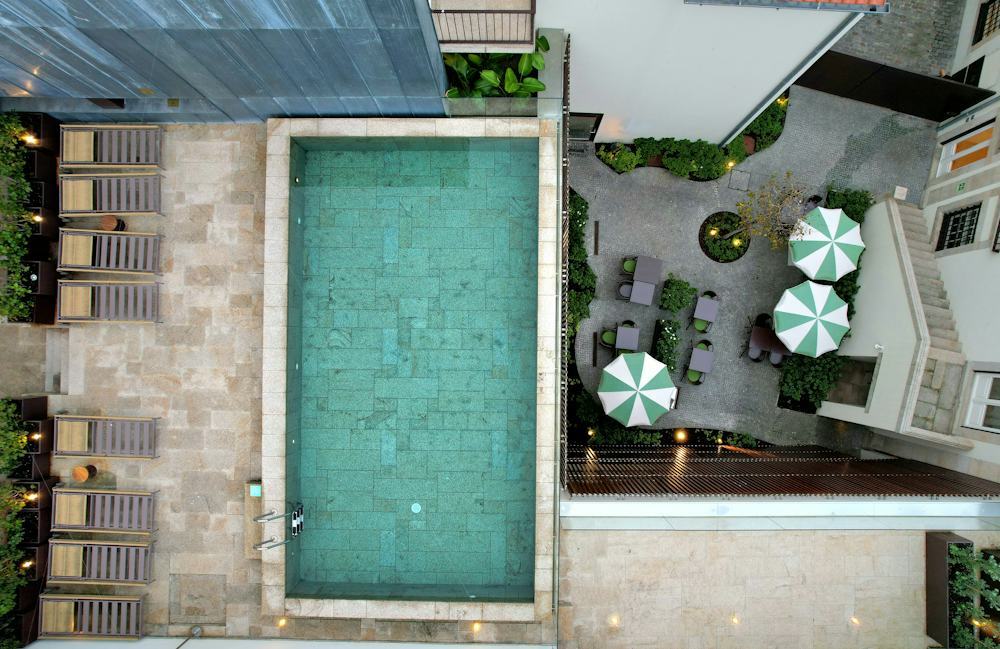 Overhead view of a courtyard with pool and umbrellas over cafe tables