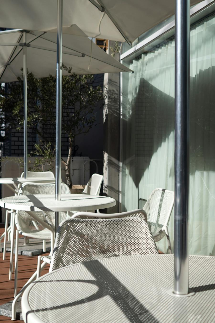 Modern terrace tables with an umbrella pole running through the centre of each table