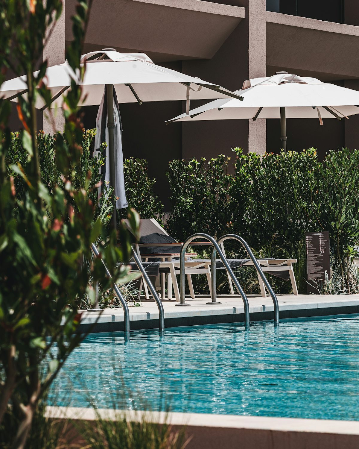 Hotel pool deck with centre-pole umbrellas standing on visible base plates