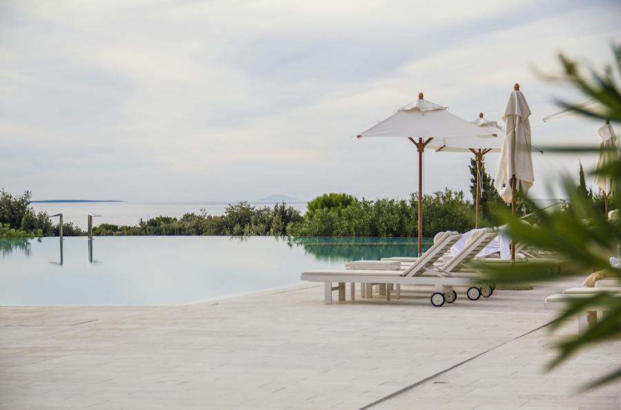 Parasols standing on a stone deck beside loungers at an infinity pool