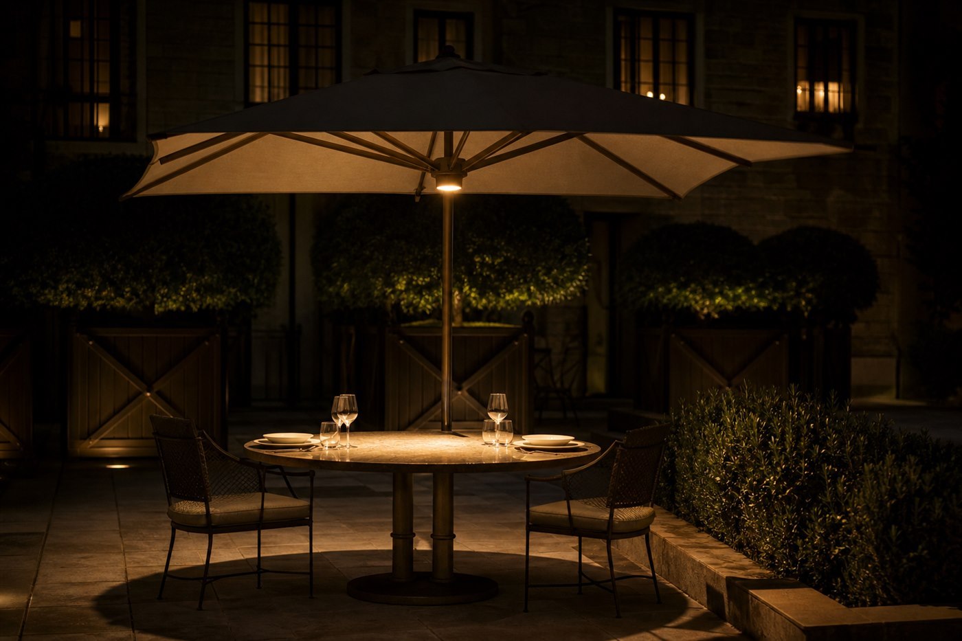 Single lamp at the centre of an umbrella canopy throwing one pool of light onto a set table at night