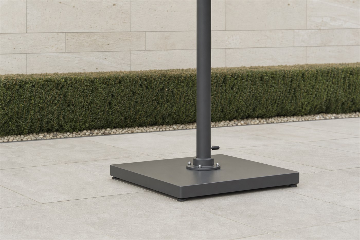 Flat base plate of a large outdoor umbrella bolted to a paved stone terrace