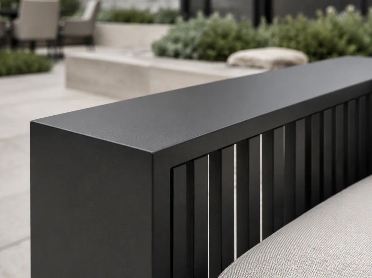 Close view of the wide flat charcoal armrest of an outdoor sofa where it meets the vertical slatted side panel