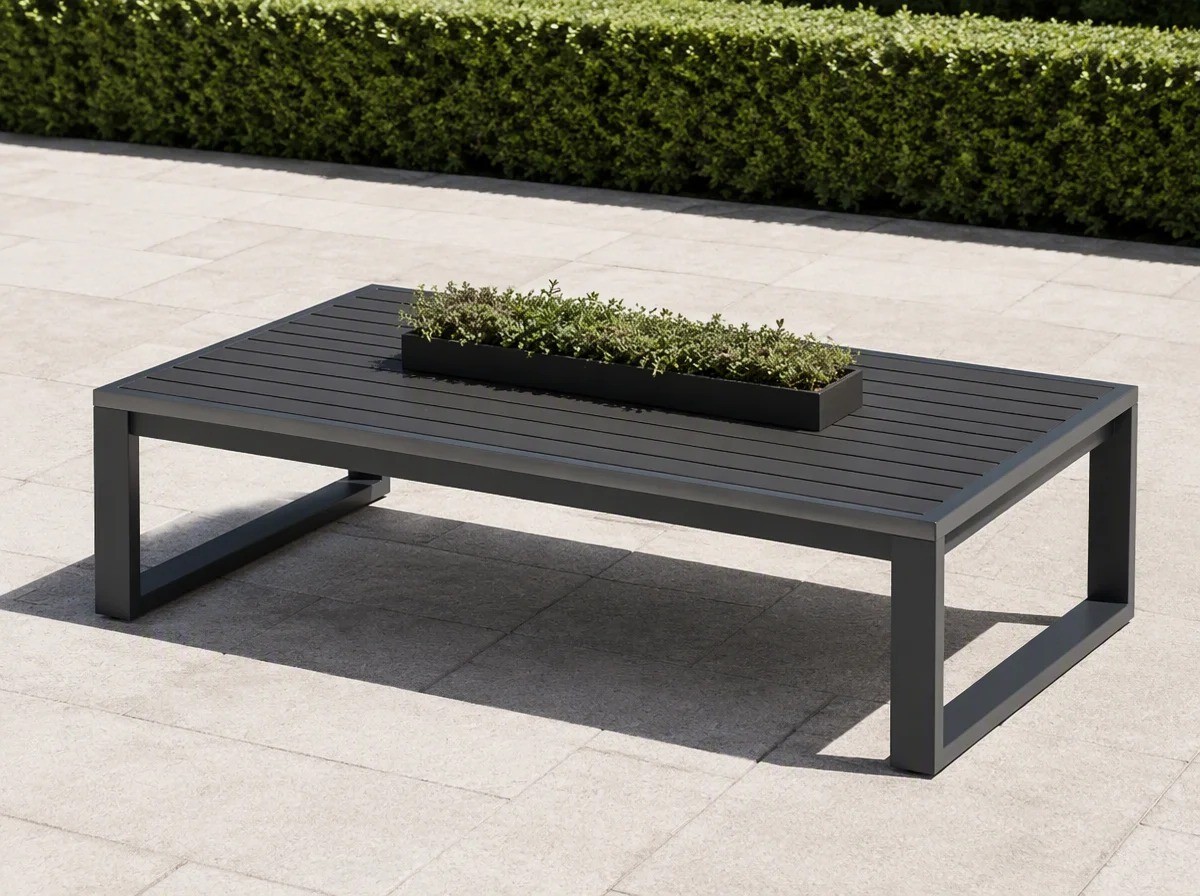 Low charcoal slatted outdoor coffee table with a shallow planter tray on pale stone paving