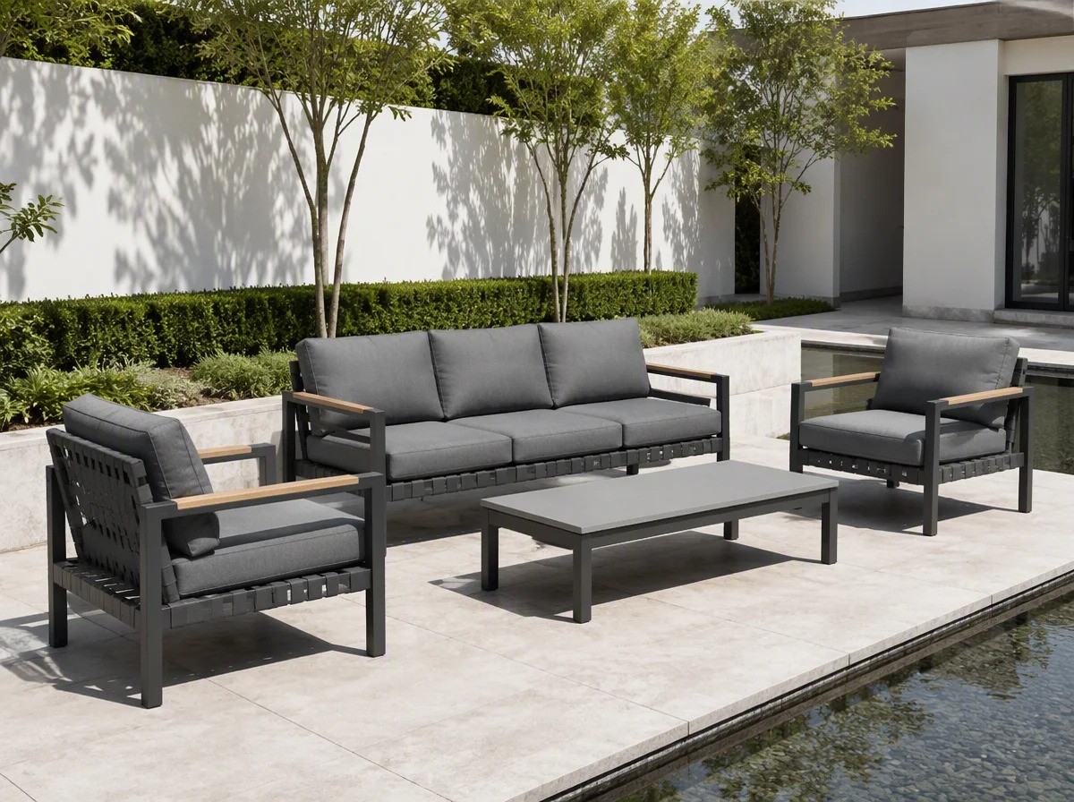 Charcoal aluminium outdoor sofa set with grey cushions beside a reflecting water feature in a modern villa courtyard