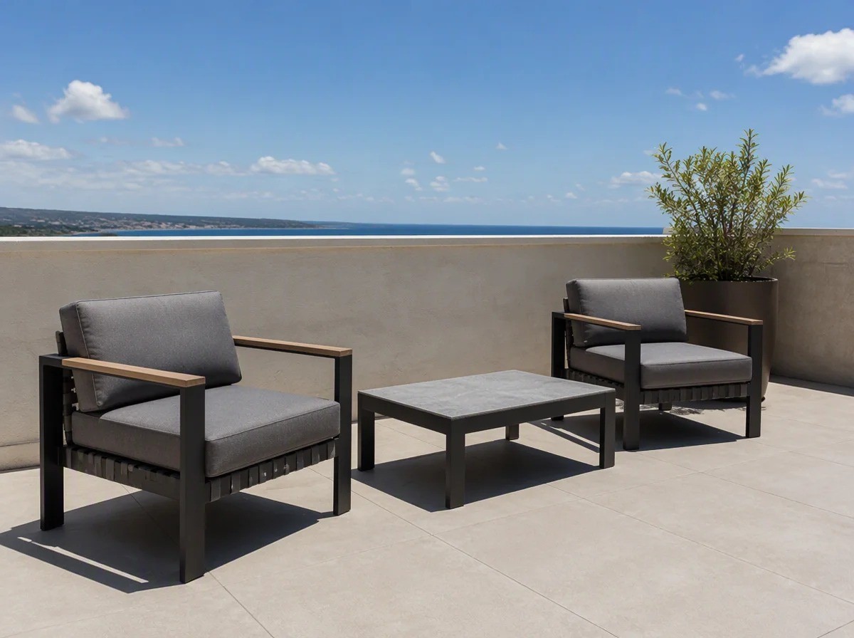Two charcoal aluminium lounge armchairs with wood-look arms and a low table on a hotel suite balcony