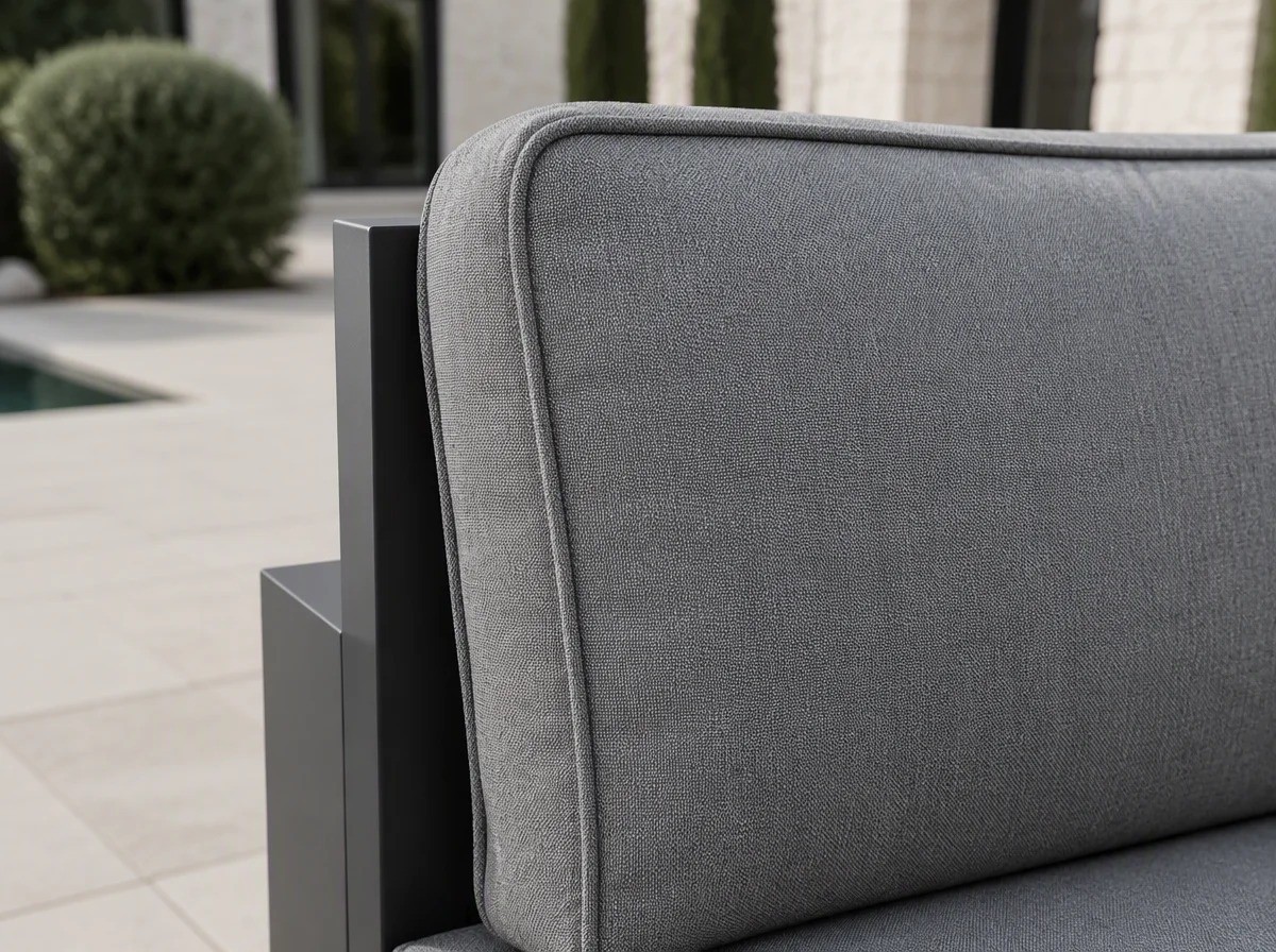 Close view of a thick mid-grey outdoor seat and back cushion with a piped edge against a charcoal aluminium frame