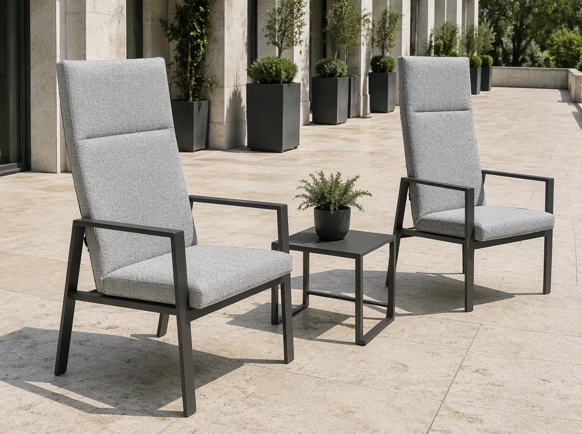 Two grey upholstered outdoor dining armchairs with a low table on a hotel terrace of pale travertine