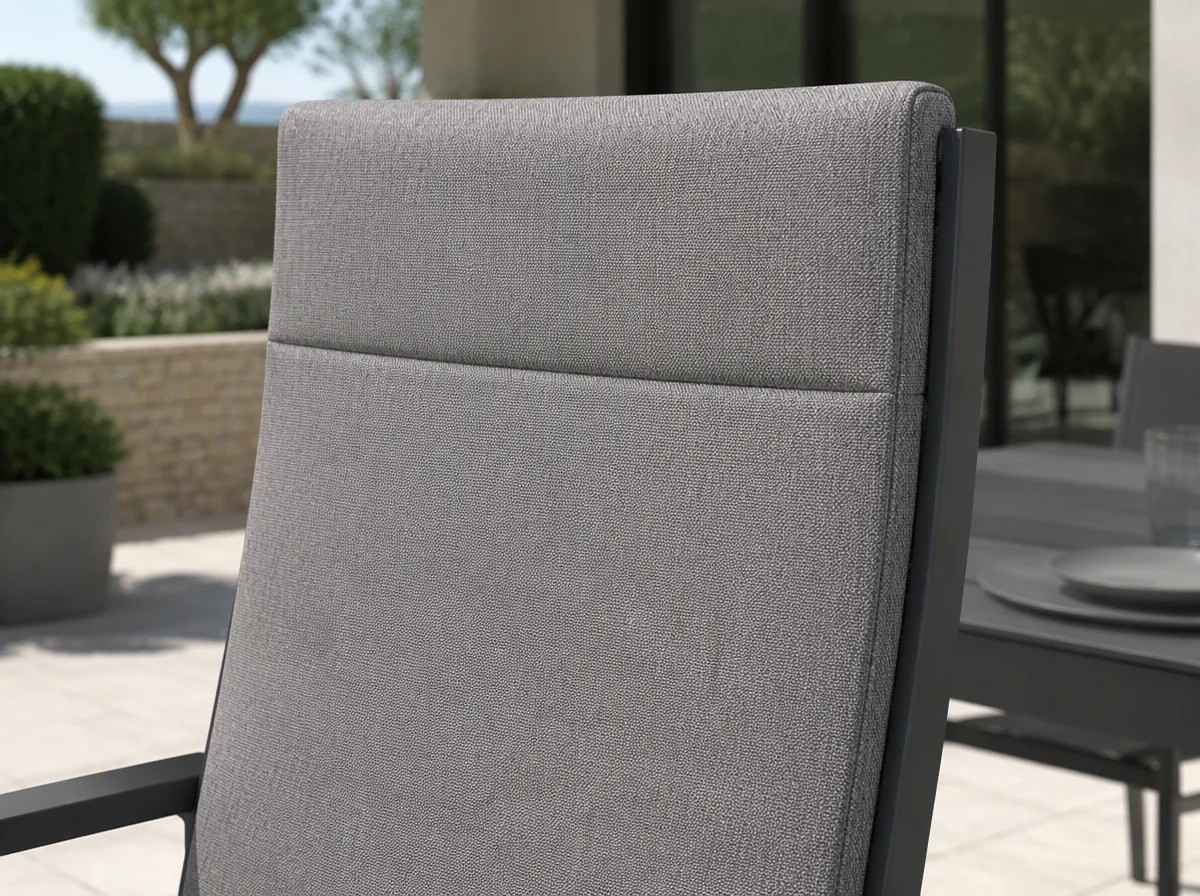 Close view of the upper part of the tall upholstered back of an outdoor dining armchair showing the horizontal seam between the two back panels