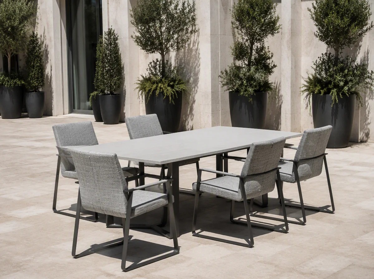 Upholstered outdoor dining chairs with grey fabric around a long dining table on a hotel terrace
