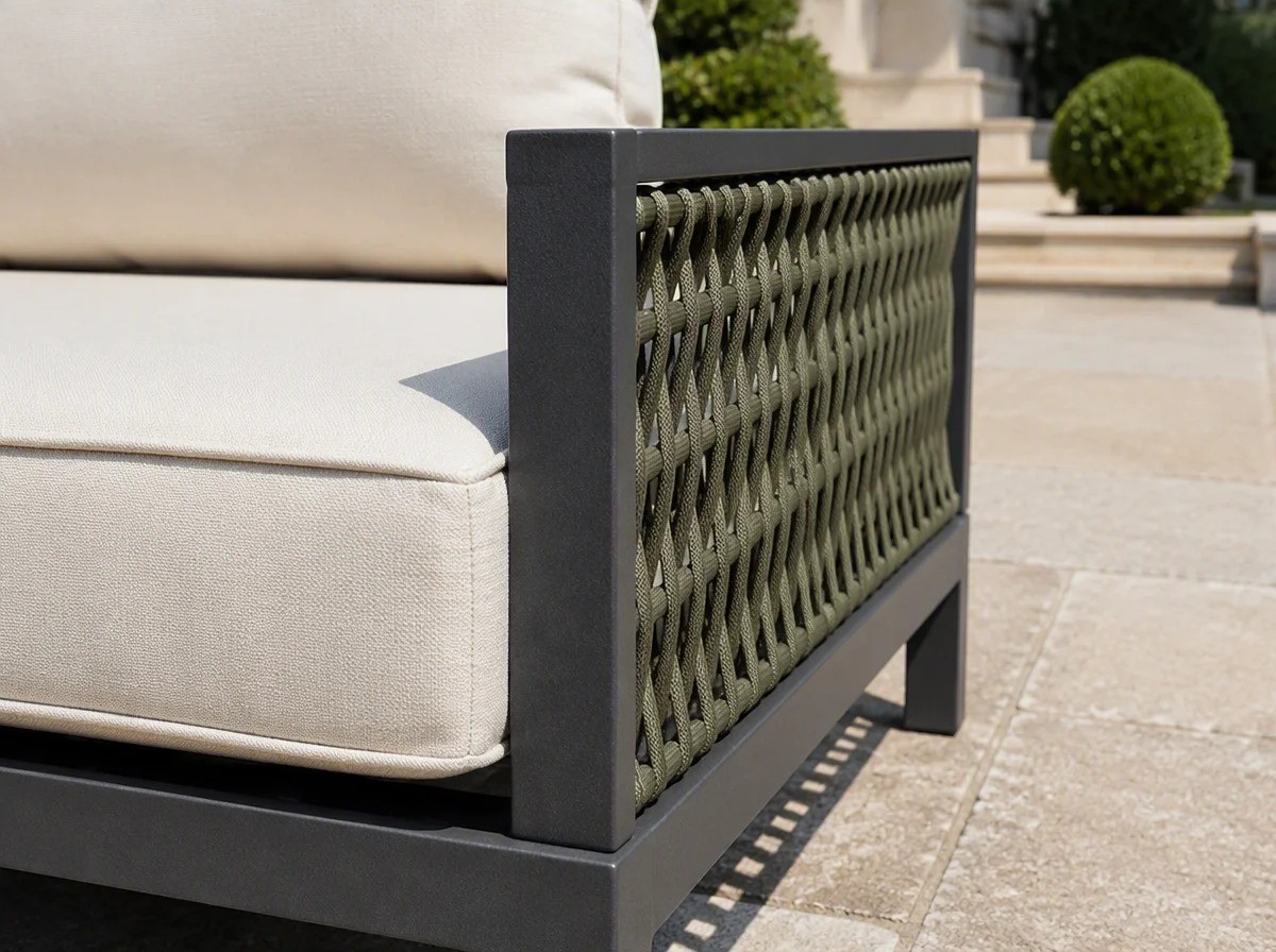 Close view of a cream quick-dry cushion beside a panel of hand-woven rope on a matt charcoal aluminium frame