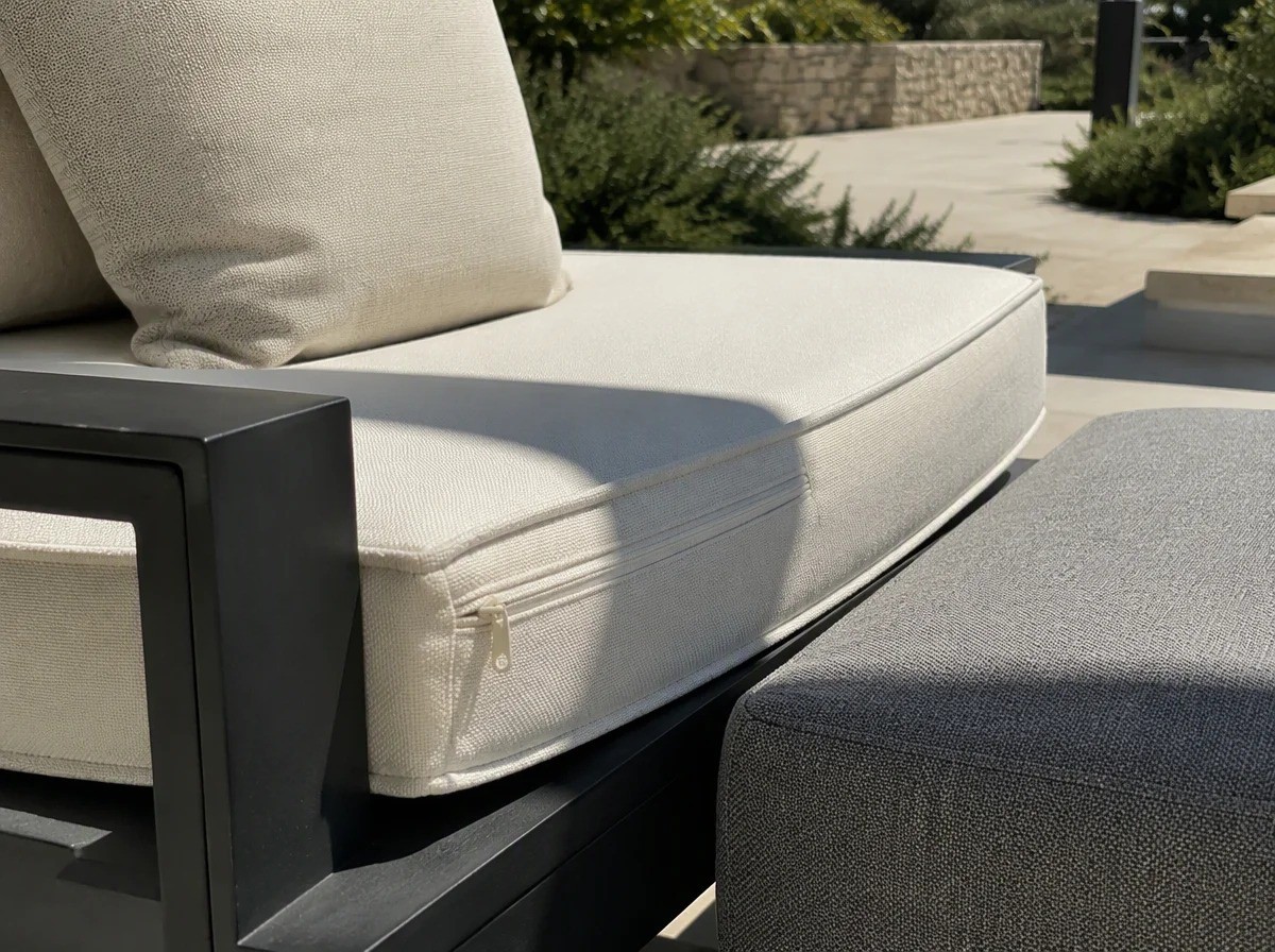 Close view of cream and grey outdoor seat cushions with a piped edge and a concealed zip on a charcoal aluminium frame