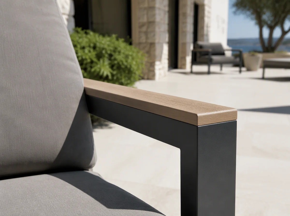 Close view of a solid light FSC teak board lying flat along the top of a matt dark charcoal aluminium armrest