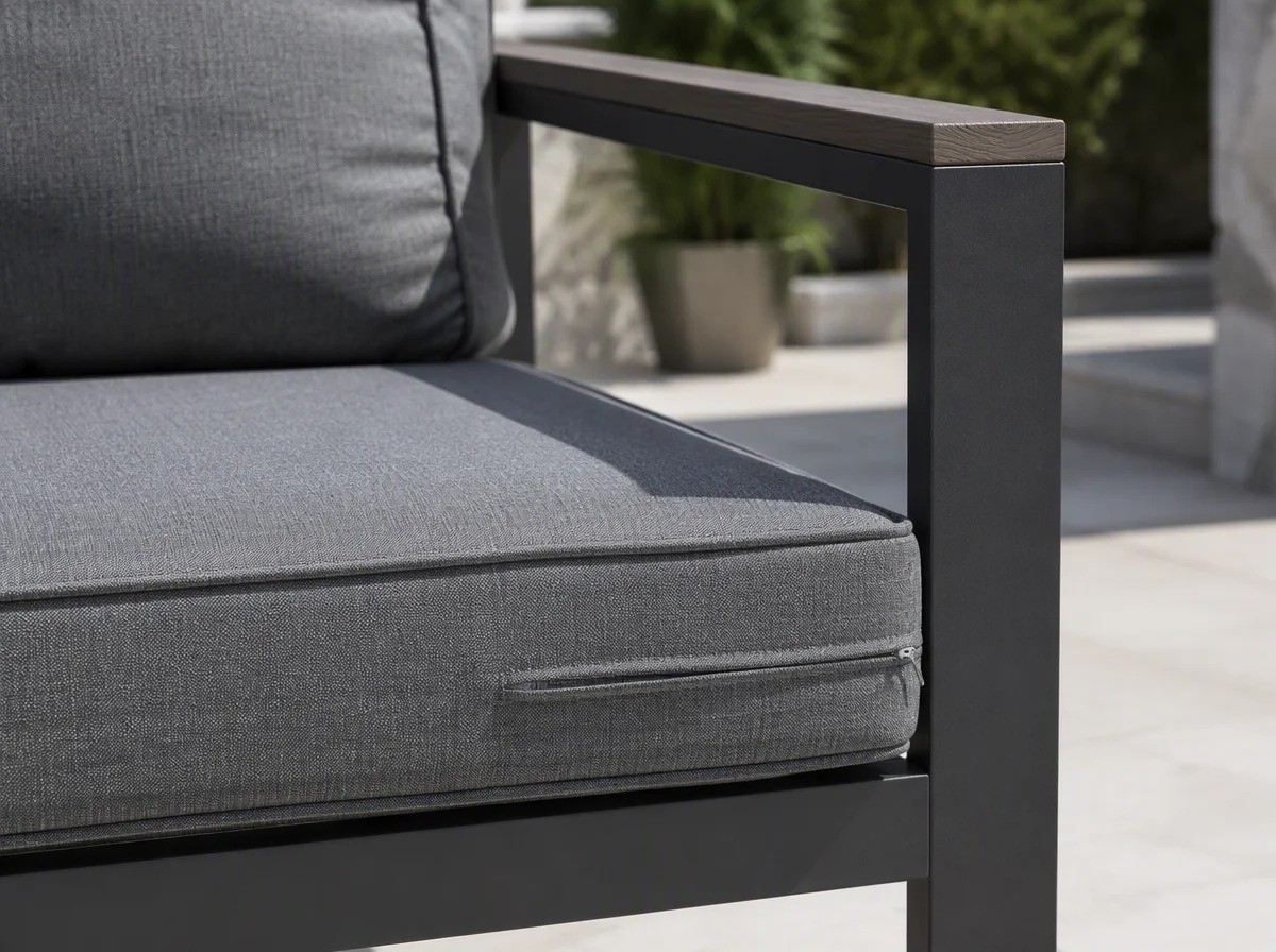 Close view of a thick mid-grey outdoor seat cushion with a piped edge and a concealed zip on a charcoal aluminium frame