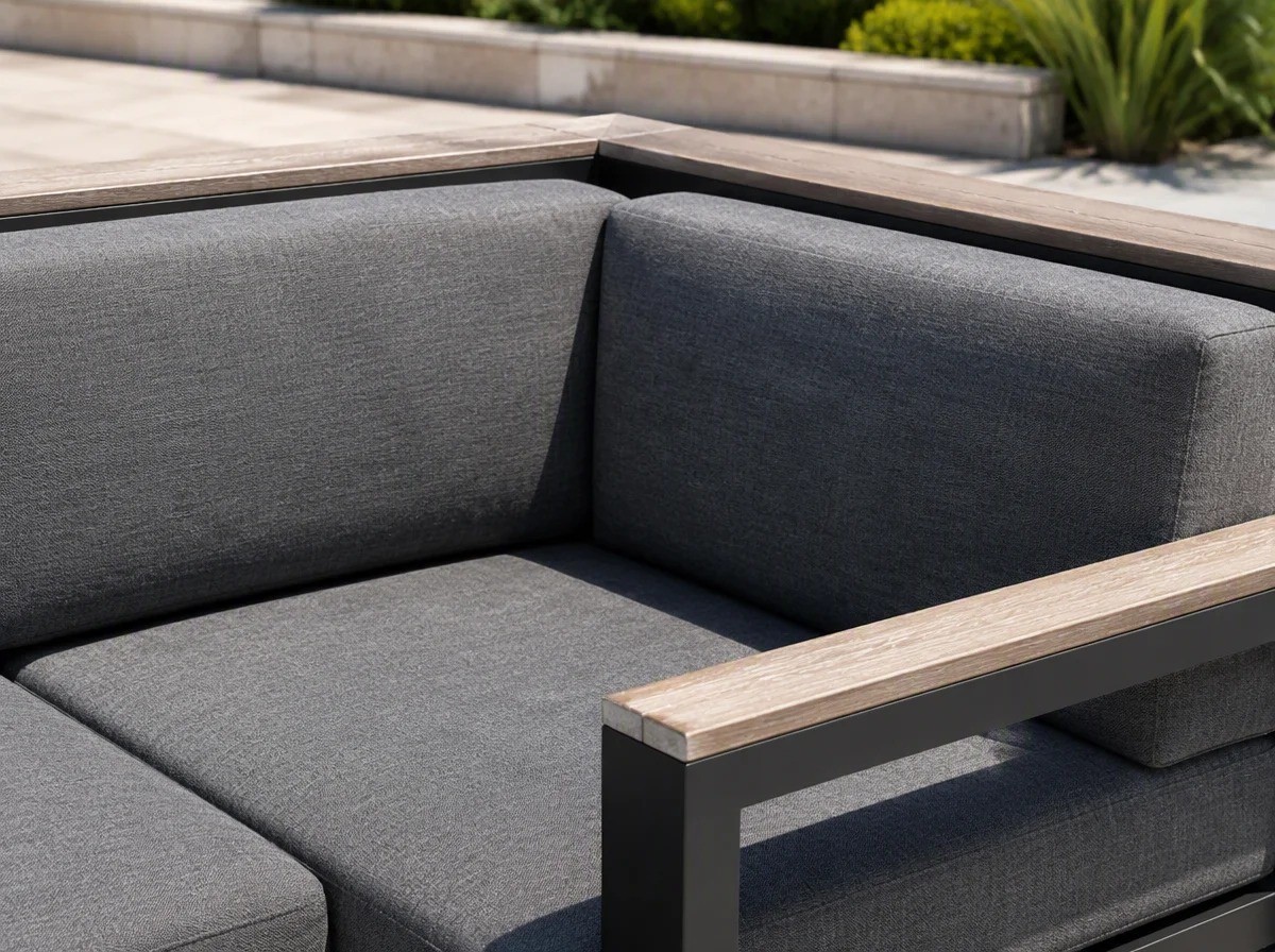 Close view of the corner of a modular outdoor corner sofa showing where one section meets the next, with teak armrest boards