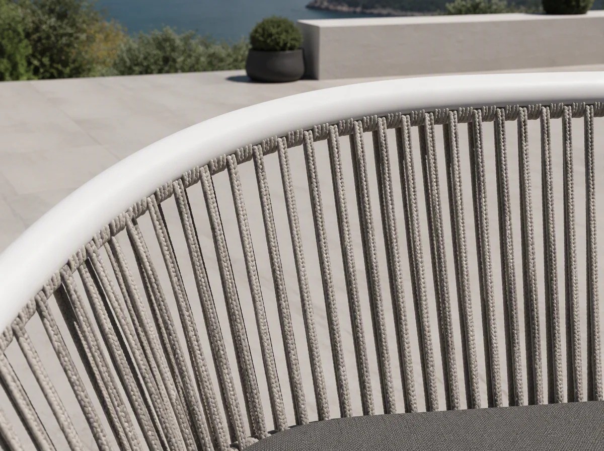 Close view of the circular barrel back of a rope-weave chair: thin vertical light grey rope strands between a white top rail