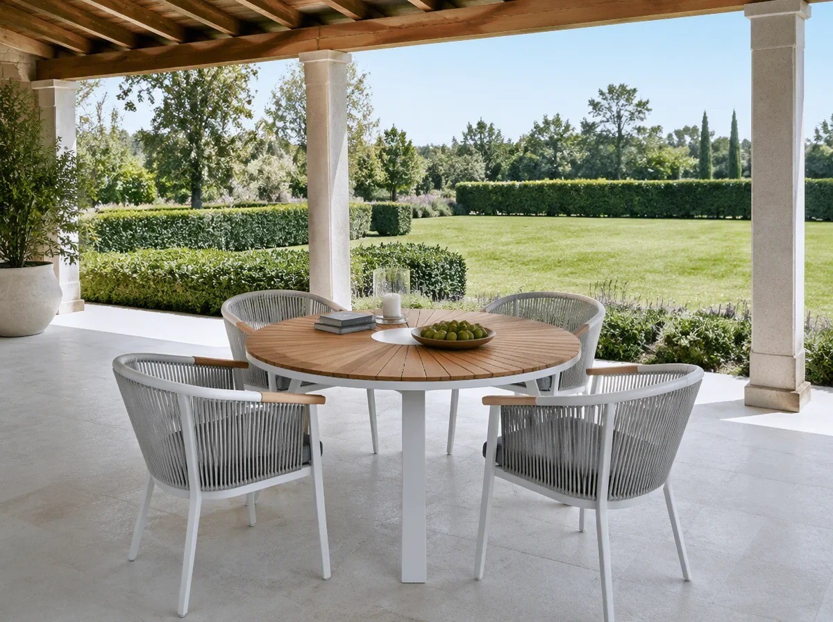 Round sunburst-slat outdoor dining table with four rope-back chairs under a covered garden pavilion