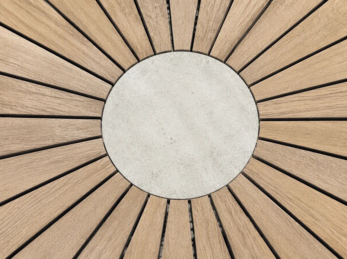 Overhead close view of a round outdoor table top: radial wood-grain slats around a solid pale circular centre insert with even dark gaps