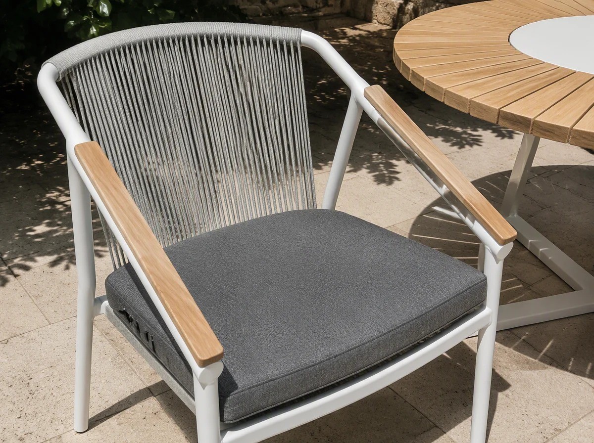 Close view of a sloping white armrest with a solid light teak board fixed along its top, and the rope back rising behind