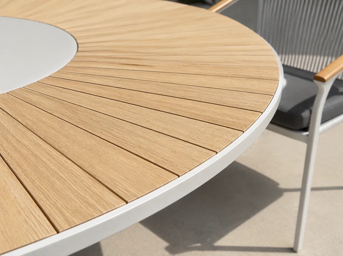 Overhead close view of a round outdoor table top: fine radial pale wheat slats around a large solid ivory circular centre insert