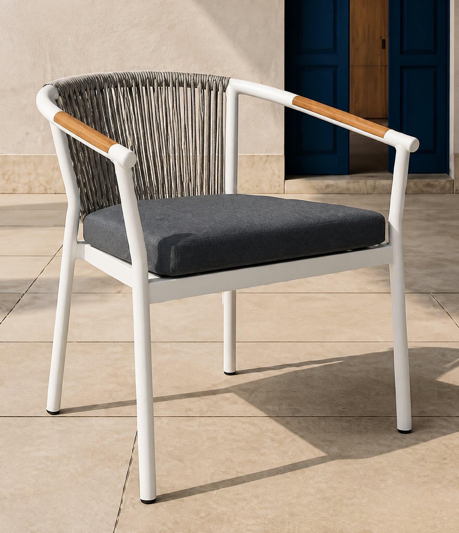 Rope weave outdoor armchair standing on a stone terrace beside a blue double doorway