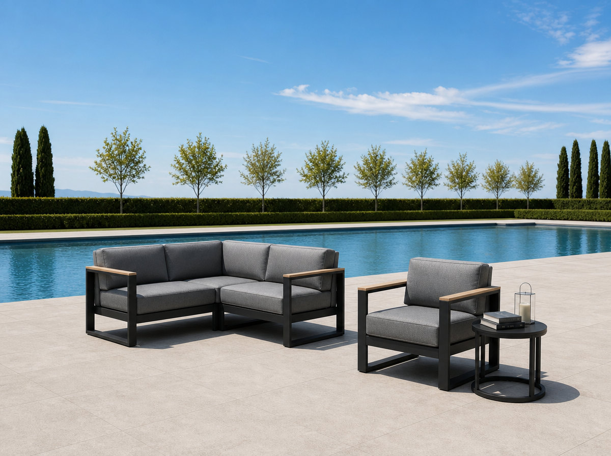 Outdoor sectional lounge group with a lounge armchair and a round side table on a resort pool deck beside still blue water