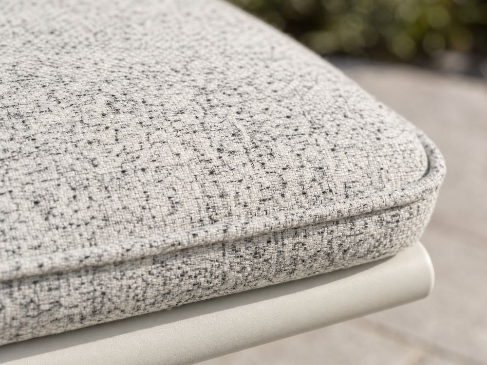 Close-up of a pale grey speckled outdoor cushion fabric with piped edge and frame tube