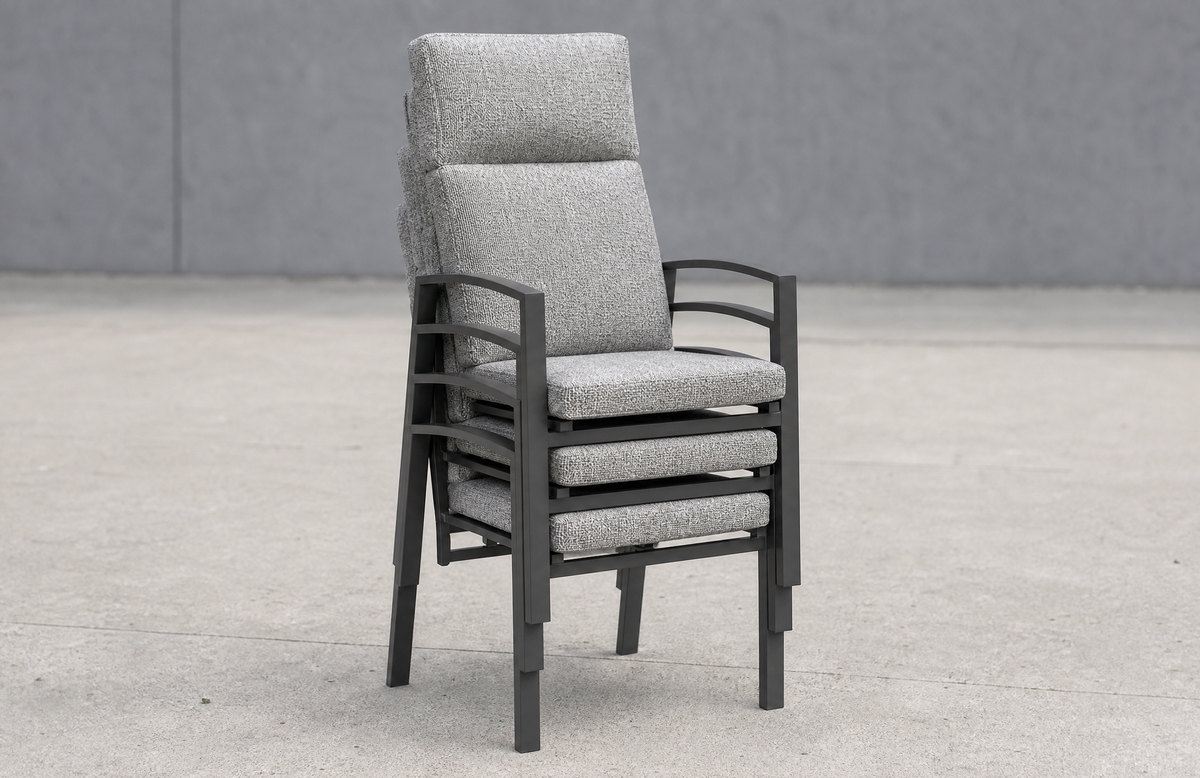 A neat vertical stack of four identical charcoal contract armchairs nested on a paved service area