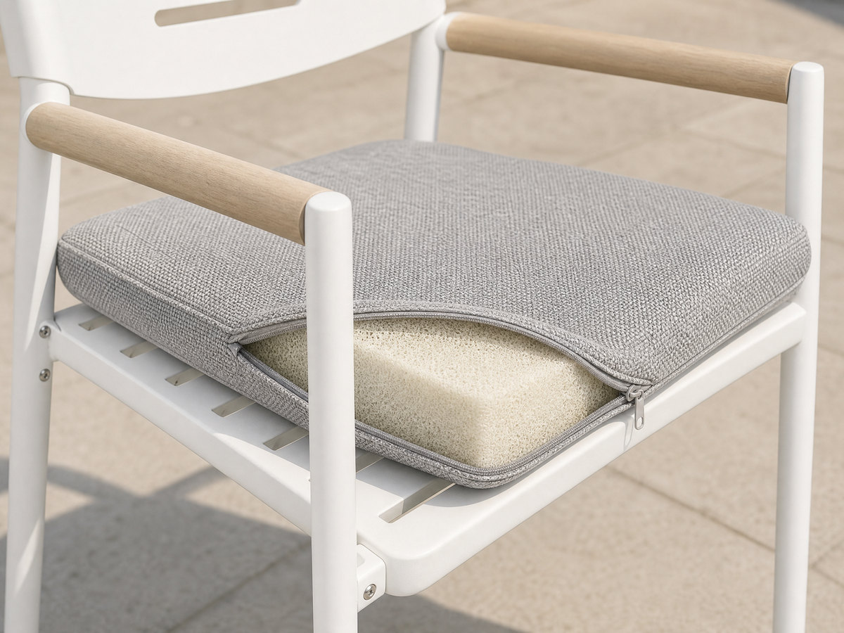 Close view of a contract outdoor chair seat with the cushion lifted to show its open-cell foam core and the slatted draining platform underneath