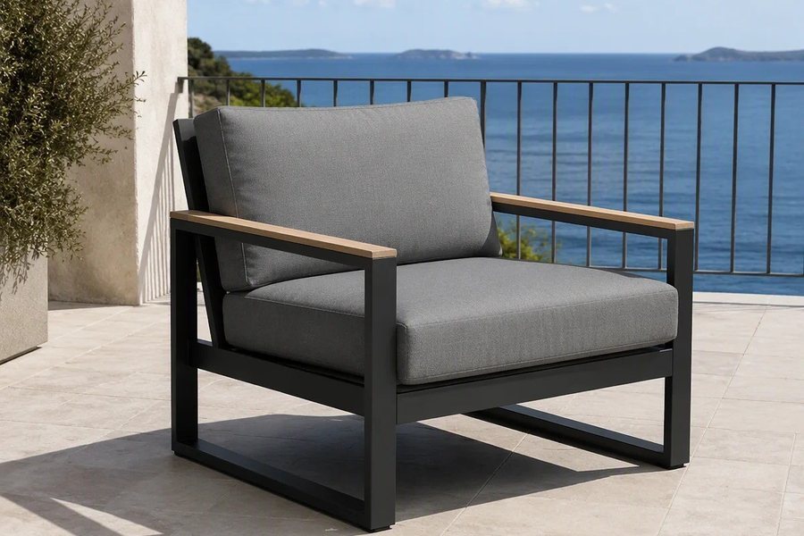 A single charcoal outdoor armchair, one module of a modular corner set, beside a glass balustrade